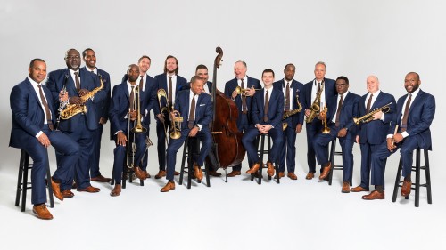 Fifteen men in blue suits hold their instruments standing shoulder to shoulder