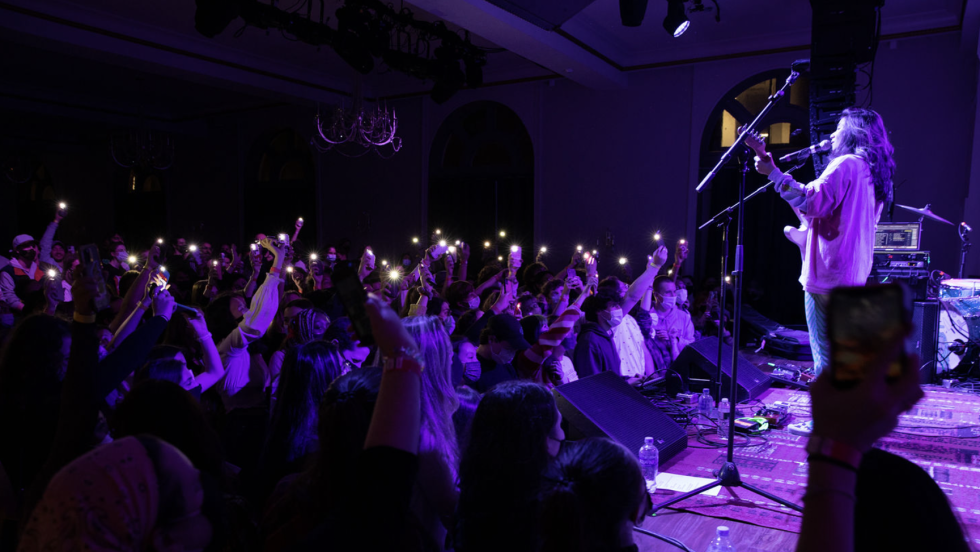 singer and crowd dance along to music under a purple light 